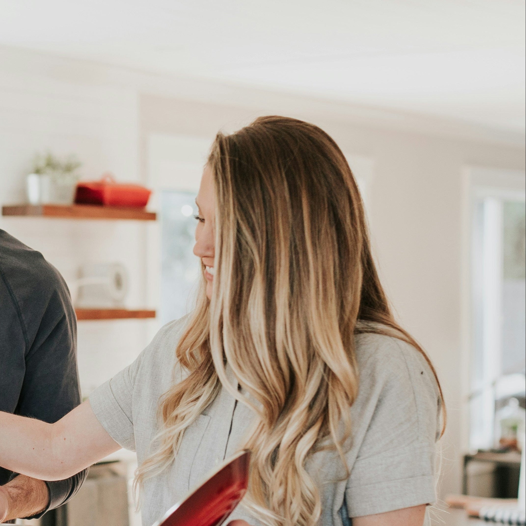 Woman with long blonde hair wearing a grey shirt in a kitchen